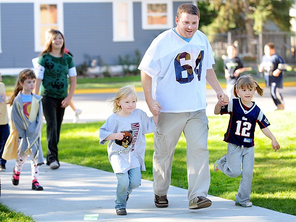 Elrod kindergarden teacher Brent Benkelman holds hands with his students Mackenzie Walhus and Abiail Swenson as they complete their last of four laps around the school on Monday in Kalispell.