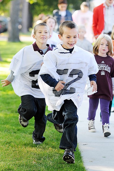 Chance Shugg, number 52, and his brother Kameron, both second graders at Elrod Elementary race around the school on Monday morning as they and their fellow students participate in the NFL Play 60 program which encourages kids to get at least 60 minutes of physical activity per day. The students began their day with an assembly in the gym followed by at least four laps around the school to complete one mile.