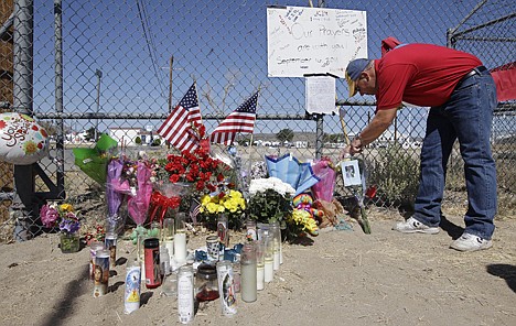 &lt;p&gt;Sean Moran picks up a petal from a memorial site of signs, flags, candles and a balloon in Reno, Nev., Sunday, near the airport where the Reno Air Races were held.&lt;/p&gt;