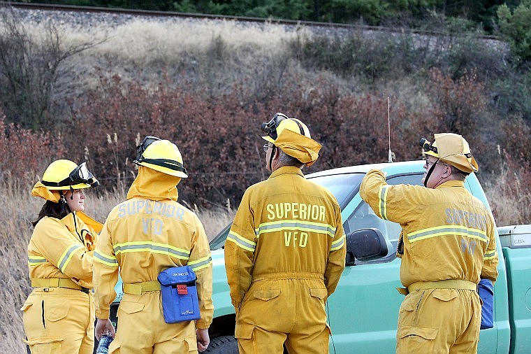 <p>Members of the Superior Volunteer Fire Department observe a small wildfire and await word to deploy on Sunday evening.</p>