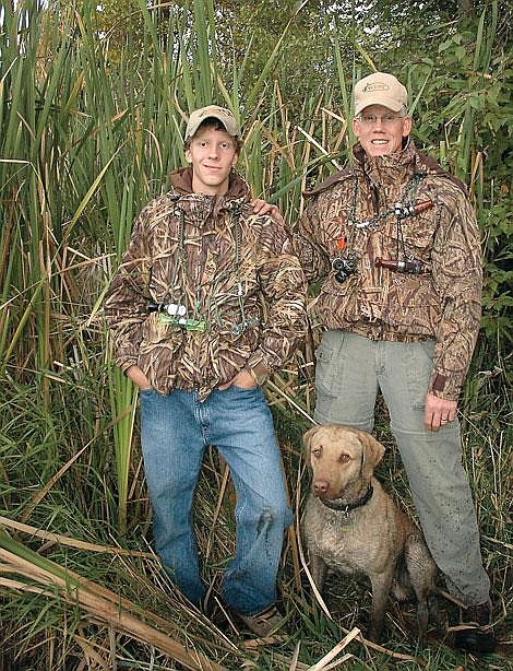 Bailey Ortley, left, and his father, David Ortley, are taking two youths waterfowl hunting this weekend as a way to encourage young people to participate in hunting. Bailey Ortley is a junior at Flathead High School and competes on the regional and national level as a waterfowl caller. David Ortley is a Flathead County justice of the peace who is an avid waterfowl hunter. Pictured with them is their Chesapeake retriever, Buck. Dave Reese/Special to the Inter Lake