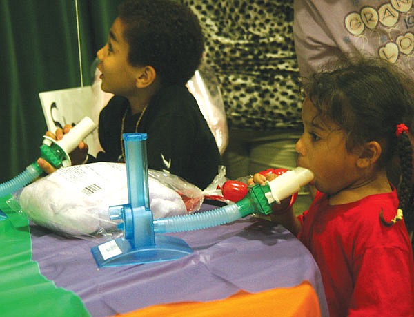 Jadeya Coleman, 3, right, and her big brother, 5-year-old Traybeon Stephens, test the capacity of their lungs as part of the educational kids carnival at the Research Rally.