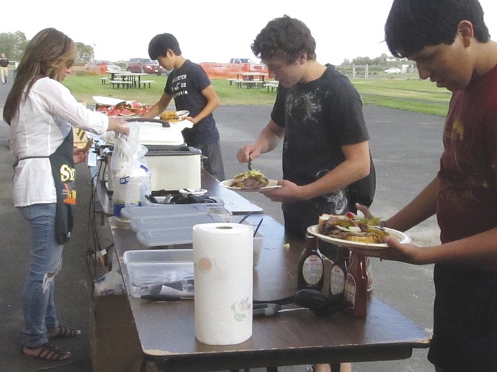 Left to right, Royal senior Noah Grant, sophomore Francisco
Godoy and junior Zack DaSilva load up with condiments, carbs and
watermelon.