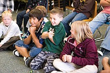 While keeping his own bones hidden, 5th grader Ethan Tolley points to the direction he thinks his opponent has hidden his clear bone during a stick game presentation by Barney Finley. His teammates, Shade Main and Marina Mayorga look on.