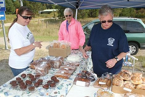 Nick Ianniello/Mineral Independent Happy Homemakers Beth Robertson, right, and Ada Messenbrink sell baked goods to Jodi Stevens Saturday morning at the Haugan exit. The Happy Homemakers are responsible for the upkeep and maintenance of the Old DeBorgia School.