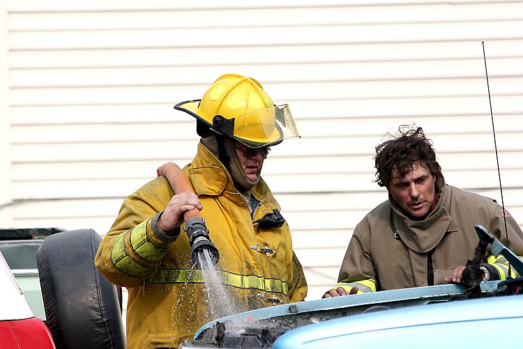 <p>Superior Volunteer Firefighters Robert Ireland and Donald Mellen work to halt a fire in the engine compartment of a car Saturday.</p>