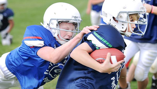 Bigfork Vikings Seth Adolph, 11, left, tackles Cody Farmer, 11, of the Domino's Pizza, Pacific Steel team from Kalispell on Saturday during the opening weekend of Little Guy football.