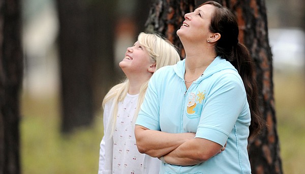 Pam Gilbert and her daughter Rebecca, 10, move around the trees in their front yard on Sunday morning looking for a different perspective of the five black bears who have taken refuge there.