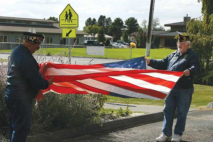 American Legion Post No. 209 adjutant Grant Oberg (left) and commander Richard Rudder unfold a new American flag, ready to be raised at the Coumbia Crest extended care facility.