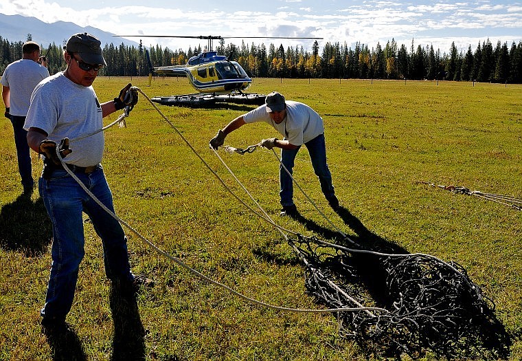 Gary Michael (left) and Grant Grisak work to pull nets apart while Mark Schnee talks on the right radio with helicopter pilot Joe Rahn.