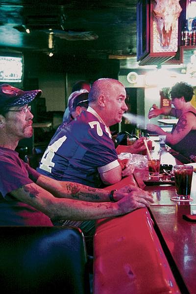 Paulie Dowdell (in hat) and Dave Murrin smoke a cigarette inside the Wolf Den bar in Polson. Starting today, smoking will be banned inside public workplaces.