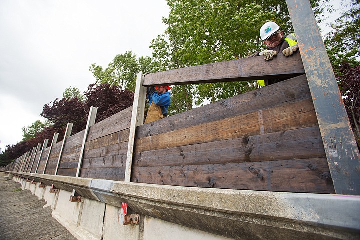 &lt;p&gt;Brad Callihan, a city employee, works with Bobby Covey to drop a treated timber in place Monday while installing an extension of the seawall near the Coeur d'Alene city beach. The flood control system project is being erected to qualify for Federal Emergency Management Agency certification.&lt;/p&gt;