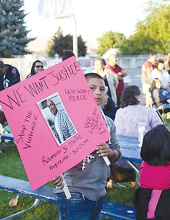 A Quincy boy holds a sign honoring Ramiro Munoz Jr., a
40-year-old father of seven who was shot and killed nearby last
Friday.