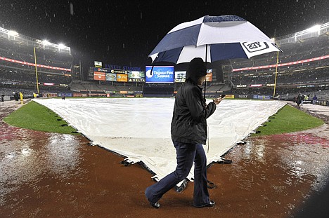 &lt;p&gt;A person walks by holding an umbrella past a tarp-covered field at Yankee Stadium after Game 1 of the American League division series between the New York Yankees and the Detroit Tigers was postponed due to rain on Friday.&lt;/p&gt;