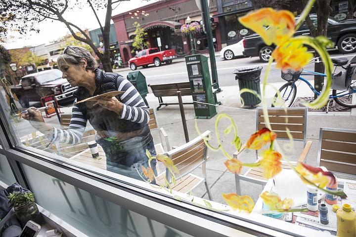 &lt;p&gt;Anne Couser paints the outside windows of Vault Coffee during the first day of fall.&lt;/p&gt;