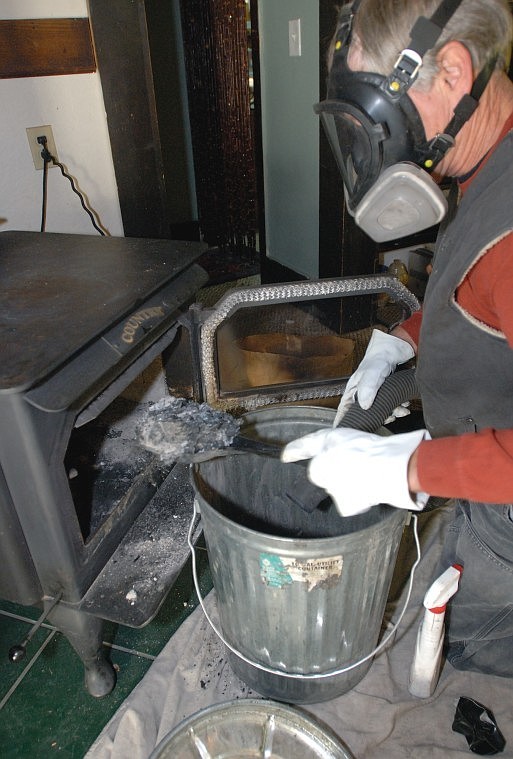 Fern scoops ash cleaned out from the chimney pipe on a wood stove at a home in Whitefish.