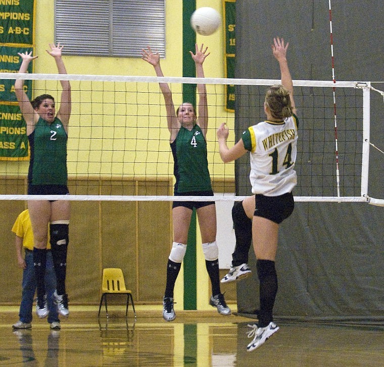 Glacier High School players McKell Bennett and Rachel Cutler (left to right) block Whitefish middle hitter Heather Bailey during the Whitefish Homecoming game Saturday night.