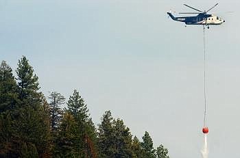 A helicopter dumps water over a forested area west of Lakeside Monday afternoon. Crews on the ground were able to continue building line around the fire's perimeter, containing 60 percent of the 220-acre fire. (Nate Chute/Daily Inter Lake)