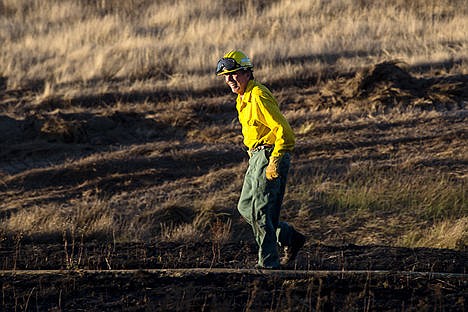 &lt;p&gt;Worley Firefighter Del Blackburn walks across a field partially burned by am estimated 100 acre wildfire that started Tuesday afternoon near Fighting Creek.&lt;/p&gt;