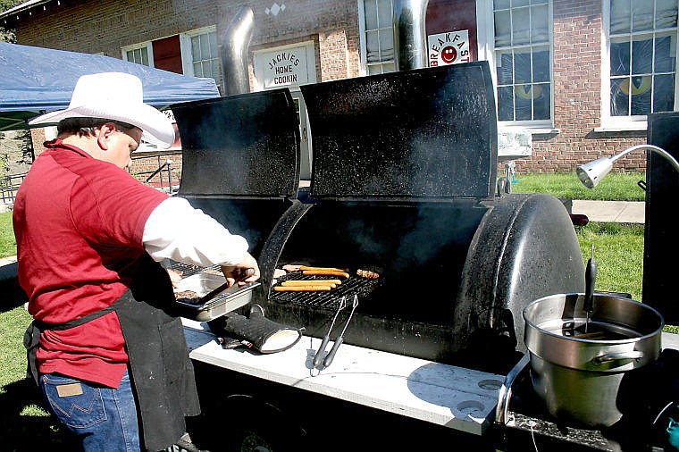 <p>Mike Perotti cooks hamburgers and hotdogs on his homemade grill outside the Old Superior Schoolhouse.</p>