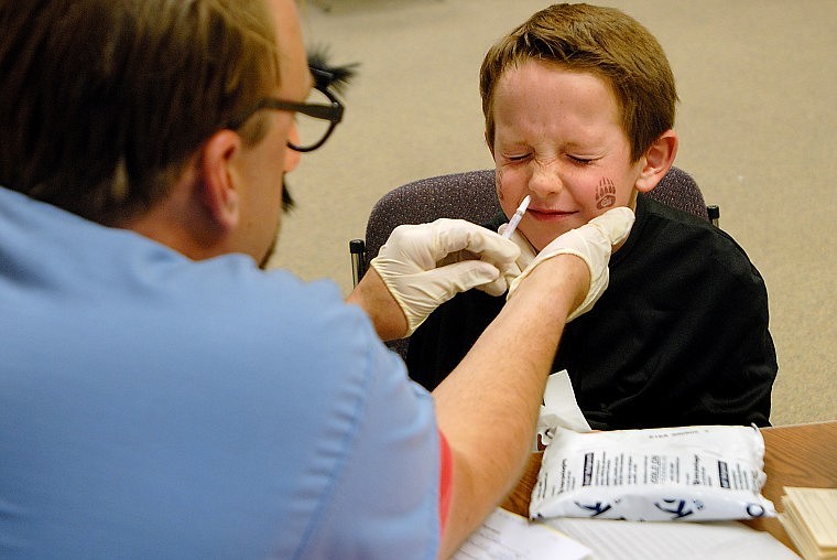 Alex Stein, 7, squints while Mike Hedstrom gives him a nasal spray as part of the first H1N1 swine flu vaccinations in the Flathead Valley on Thursday morning at the Flathead City-County Health Department in Kalispell.