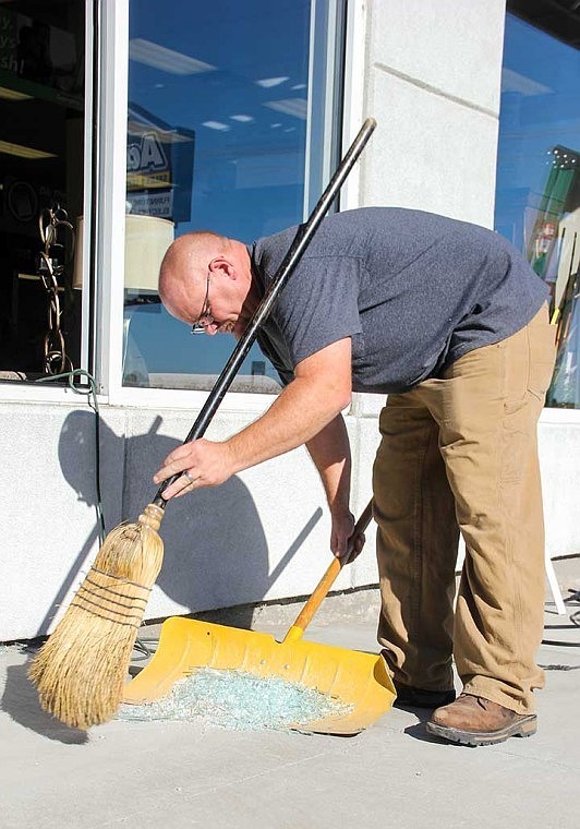 Justin Vanerstrom, of Al's Glass Service, sweeps up glass shards from windows broken at Aaron's Wednesday morning.