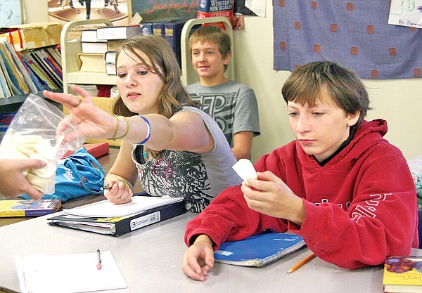 Troy eighth-graders Paige Shaver and Noah Erickson pick out a slice of turnip, a common food in Pakistan, during an activity to correspond with their reading of the book, &#147;Three Cups of Tea.&#148;