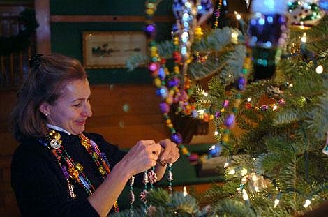 Karen Nichols/Daily Inter Lake &#151; Rita Fitzsimmons, who has been helping decorate for Christmas at the Mansion for about 20 years, hangs garlands on the top of the 20-foot grand fir that fills the two-story great hall of the Conrad Mansion in downtown Kalispell. Fitzsimmons, who leads the great hall decorating, was among about 25 people who gathered at the mansion Sunday afternoon to deck the halls of the historic home.