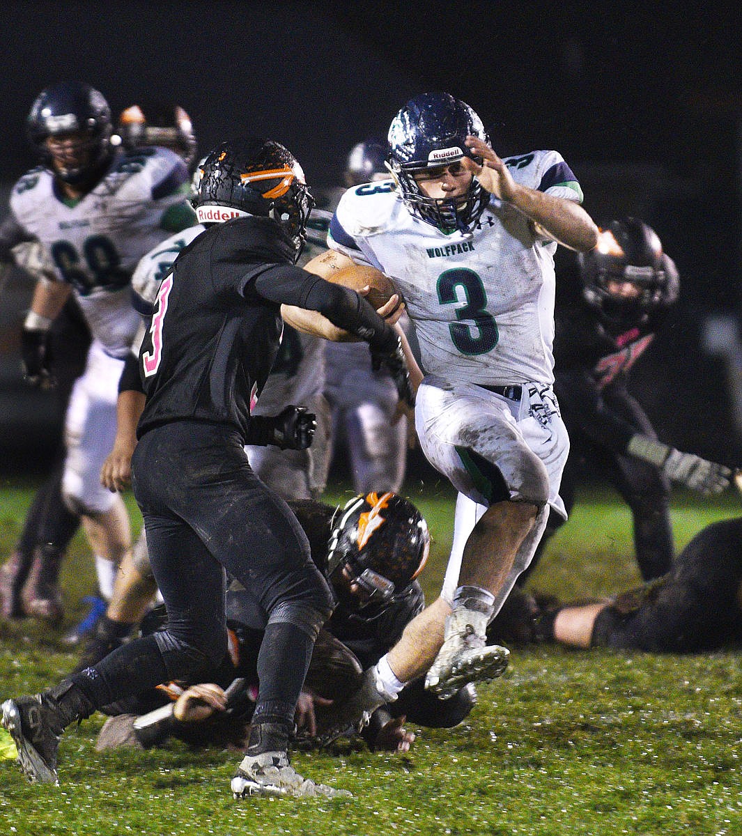 <p>Glacier quarterback Taden Gilman breaks the tackle of a couple of Flathead defenders as he goes on a long run to set up a Wolfpack touchdown to open the third quarter at Legends Stadium on Friday. (Aaric Bryan/Daily Inter Lake)</p>