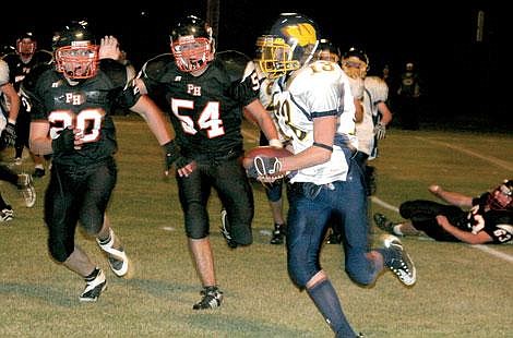 Jamie Doran/Valley Press Isaiah Joner and Steven Reistroffer rush towards a Warden player on defense. The Savage Horsemen won 36-0.