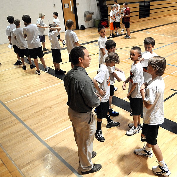 A group of students gather around Kalispell Middle School Activities Director Dallas Stuker at the start of basketball tryouts on Monday, October 18. Two gyms and four sessions were used to divide the students up into manageable groups.