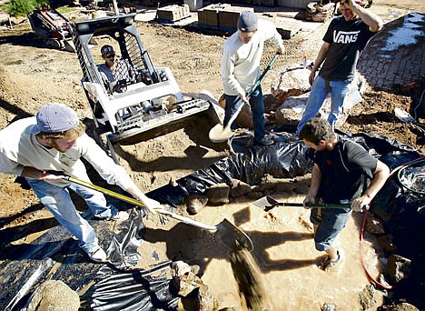 &lt;p&gt;From left, KW Hardscape employees Seth Huffman, Armando Cuevas, Joe DeArrman, Todd Lockwood and Eric Hengehold build an accent pond Thursday in Chandler, Ariz. Fewer people applied for unemployment benefits last week in the state, but the drop wasn't enough to reverse a big increase the previous week.&lt;/p&gt;