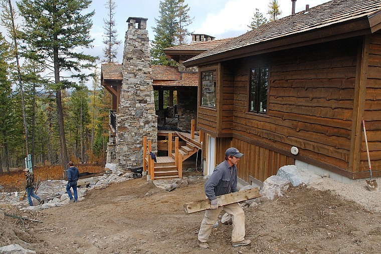 Bobby Cartwright carries a piece of wood to the other side of a house in the Saddlehorn subdivision near Bigfork on Thursday afternoon. Some 46 lots out of 60 in the first phase of Saddlehorn have been sold.