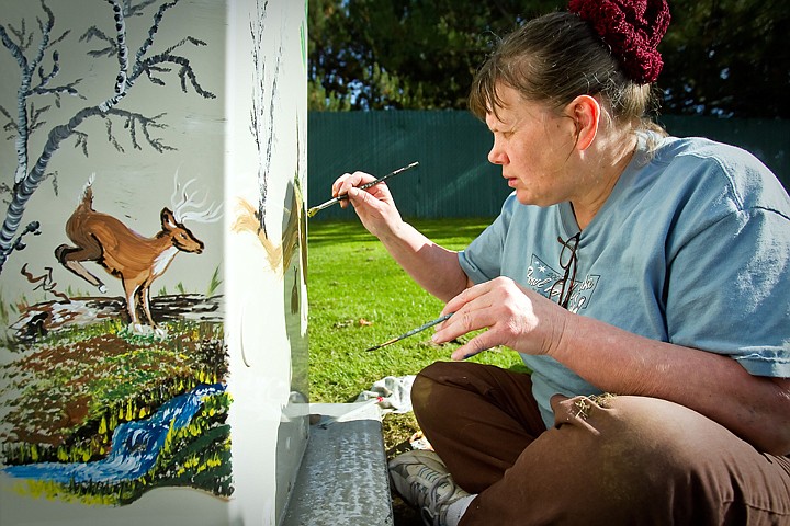 &lt;p&gt;JEROME A. POLLOS/Press Jean Selman paints a nature scene on a utility box Monday across the street from Marie Luke's home on 19th Street in Coeur d'Alene. Luke commissioned Selman to paint the large, metal box after she spoke with a Frontier Communications representative about minimizing its visibility after it was installed. &quot;It's right there in plain sight right out my front door,&quot; Luke said.&lt;/p&gt;