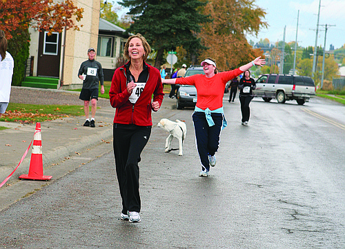 Peggy Young and Jennifer Fisher smile down the homestretch of the Live Locally 5k Run Saturday in Polson.