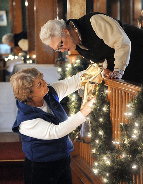 <p>Carol McElwain, left, of Columbia Falls, helps Kathy Mercord of
Lakeside, add a string of lights to the draped greenery on Sunday
afternoon at the Conrad Mansion.</p>