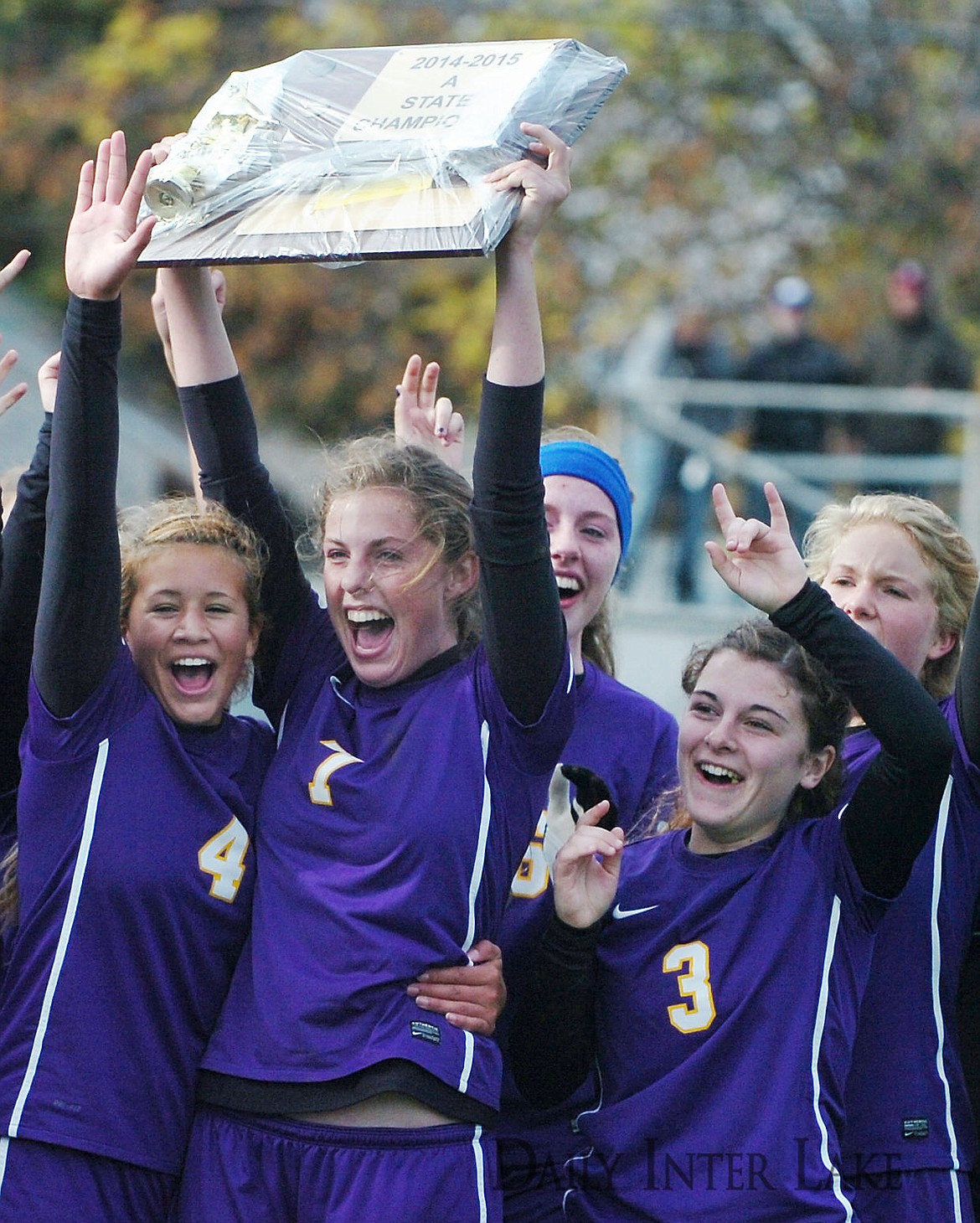 <p>Laurel's Allie McGrath (7) holds up the championship plaque as her teammates Raquel Jimenez (4) and Kyra Elmer (3) celebrate their 2-1 win over the Wildkats in the Montana Class A Championship in Columbia Falls Saturday. (Aaric Bryan/Daily Inter Lake)</p>