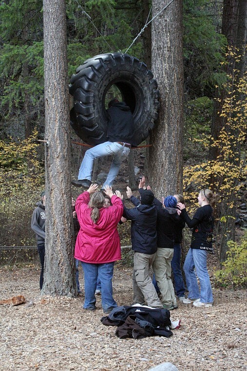 To promote team-work and good decision making, junior class members assists each other in climbing through an elevated tractor tire at Camp Bighorn.