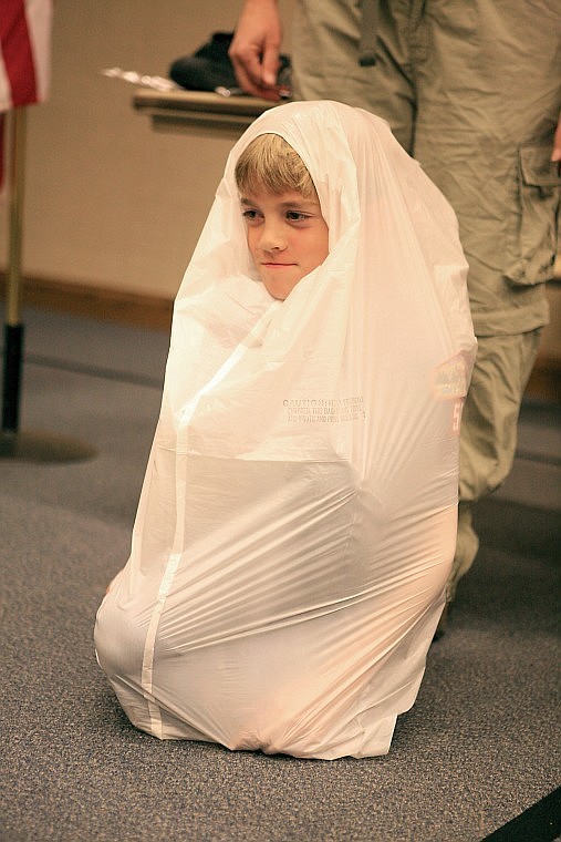 Bridger Foust wraps himself up in a garbage bag shelter that will keep him warm and dry if he should get lost in the woods.