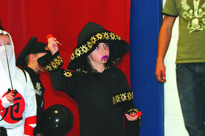 Bailey Milender throws a dart at the balloons on Sunday night during Superior's Halloween Party.