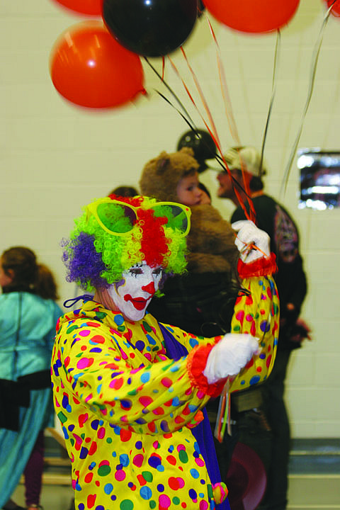 Dressed as a clown, Micki Tourtelette hands out a balloon on Sunday.