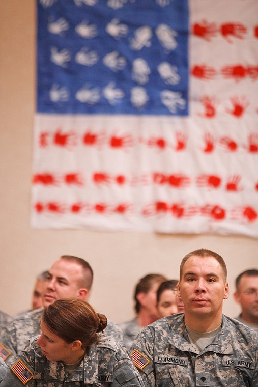 <p>Patrick Cote/Daily Inter Lake Members of the Montana Army National Guard's 495th Combat Sustainment Support Battalion wait for the deployment ceremony to begin Monday afternoon at the Hilton Garden Inn. The flag on the wall was created by friends and family of the 495th during a Yellow Ribbon event earlier this year. The battalion will bring the flag to Afghanistan where it will hang in their command center. Monday, Nov. 5, 2012 in Kalispell, Montana.</p>