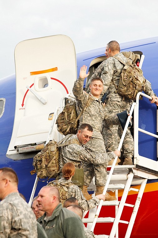 <p>Patrick Cote/Daily Inter Lake Soldiers look back to wave to friends and family as the board the plan Tuesday morning during the deployment of the Montana National Guard's 495th Combat Sustainment Support Battalion from the Glacier Jet Center at Glacier International Airport. Tuesday, Nov. 6, 2012 in Kalispell, Montana.</p>