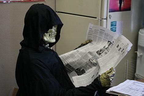 Jamie Doran/Valley Press The Grim Reaper, aka Jim Arnold, kicks back and takes in the obituary section of the newspaper Friday inbetween spooking students.