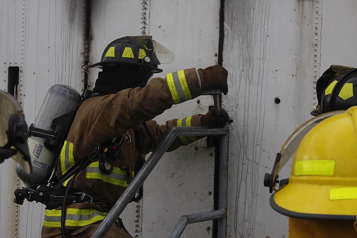 Trevor Sheridan employs a Halligan tool to pry open the door of the training trailer.