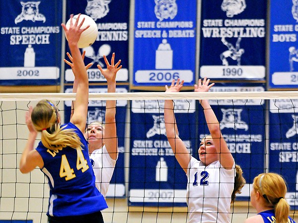 Columbia Falls's Gabrielle Stenger and Niki Birky (12) jump up with their arms raised to block the spike of Libby's Lauren Wepprecht (44) during the Northwestern A Divisional Volleyball Tournament in Columbia Falls on Friday.