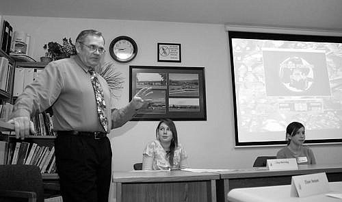 Polson Middle School teacher and founder of the Pirates News Network (PNN) Clay Herring addresses the attendees of Superintendent McCormick's monthly community meeting after showing this school year's first episode. He is accompanied by seventh grade reporter Emmy Driscoll, middle, and PNN's producer, seventh grader Sheridan Russell, right. Photo by Mike Cast