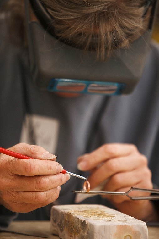 <p>Kris Kramer applies solder to a ring Oct. 21 during a copper cabochon ring class taught at Powder Horn Trading Company.</p>