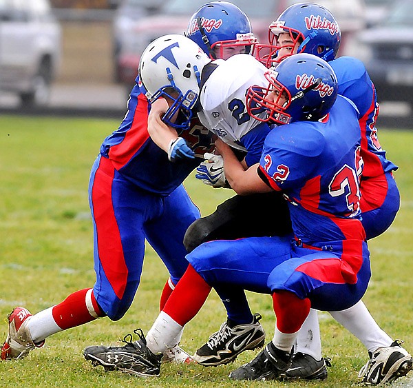 From left to right, Bigfork's Blake Weimer, Kenji Sagami, and Alex Ruiz (32) come together to bring down Townsend's Zach Spritzer (22).