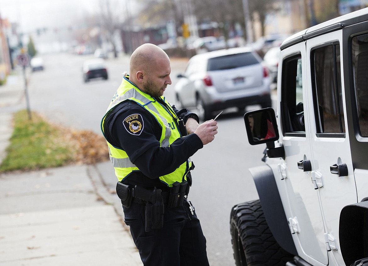 &lt;p&gt;Coeur d'Alene Police officer Spencer Mortensen looks at a license and issues a warning to a driver for going above the speed limit on 3rd street in downtown Coeur d'Alene on Wednesday.&lt;/p&gt;